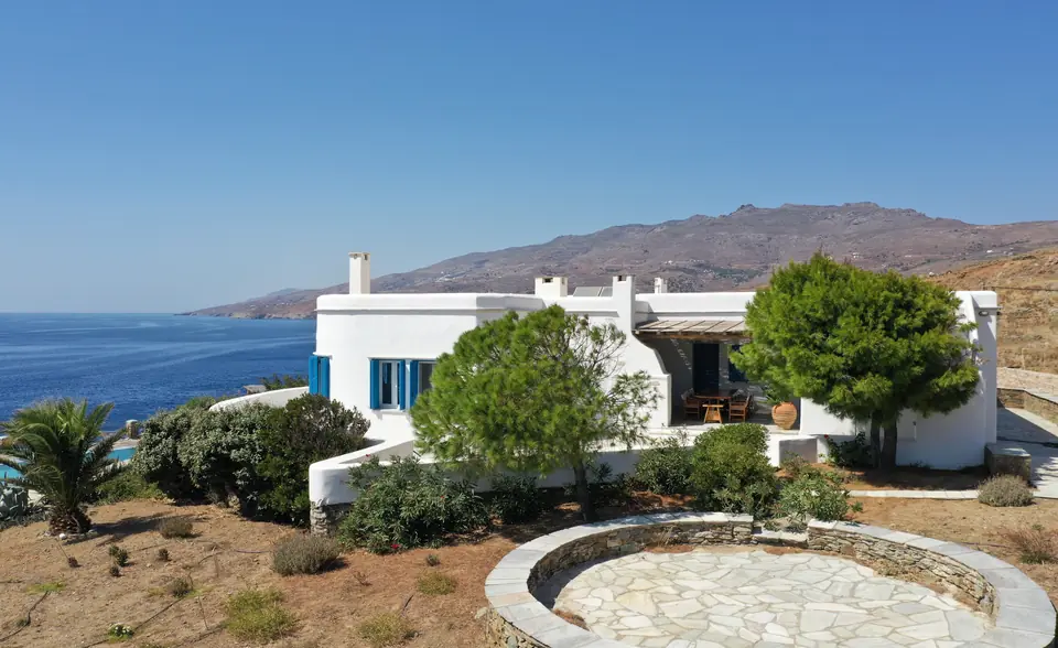The whitewashed villa among the garden, with the sea and the hills of Tinos